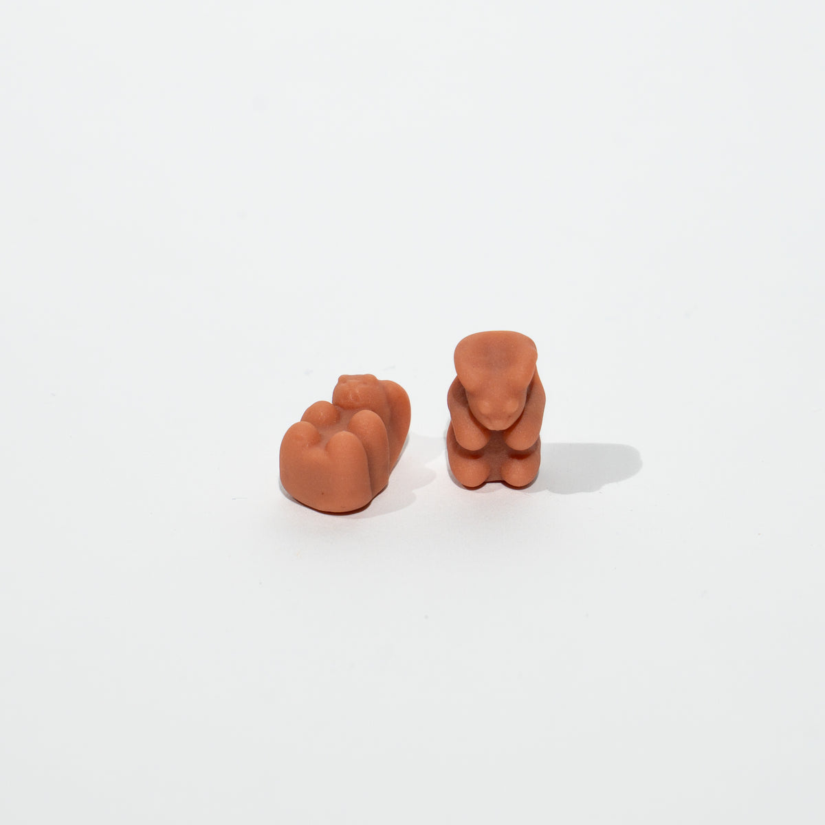 Two terracotta-colored gummybears on a white background