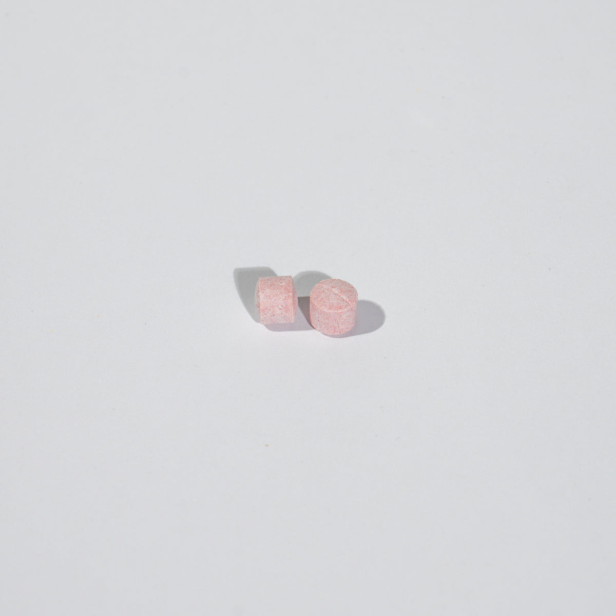 Pair of pink tablets on a light gray background