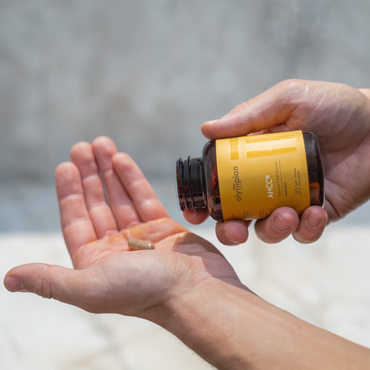Person holding a bottle of supplement with a blurred natural background