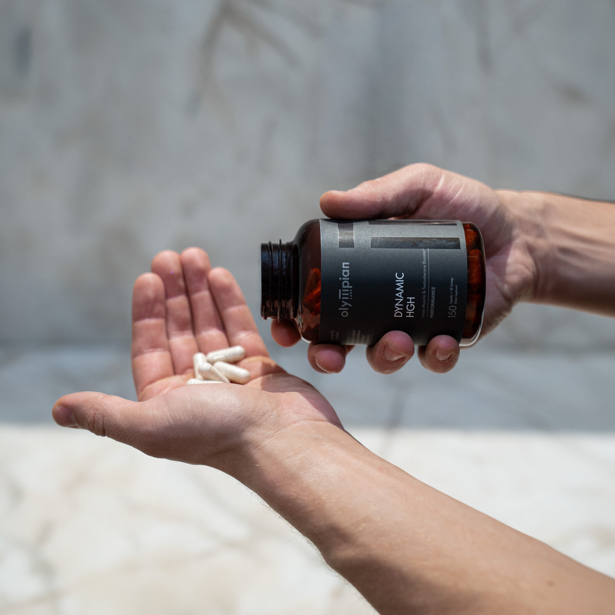Person holding a bottle of supplements with pills in their hand against a neutral background