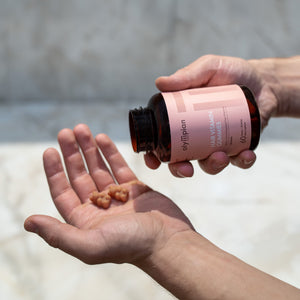 Person holding a bottle of vitamins with a blurred background