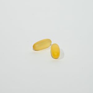 Two yellow softgels on a light gray background