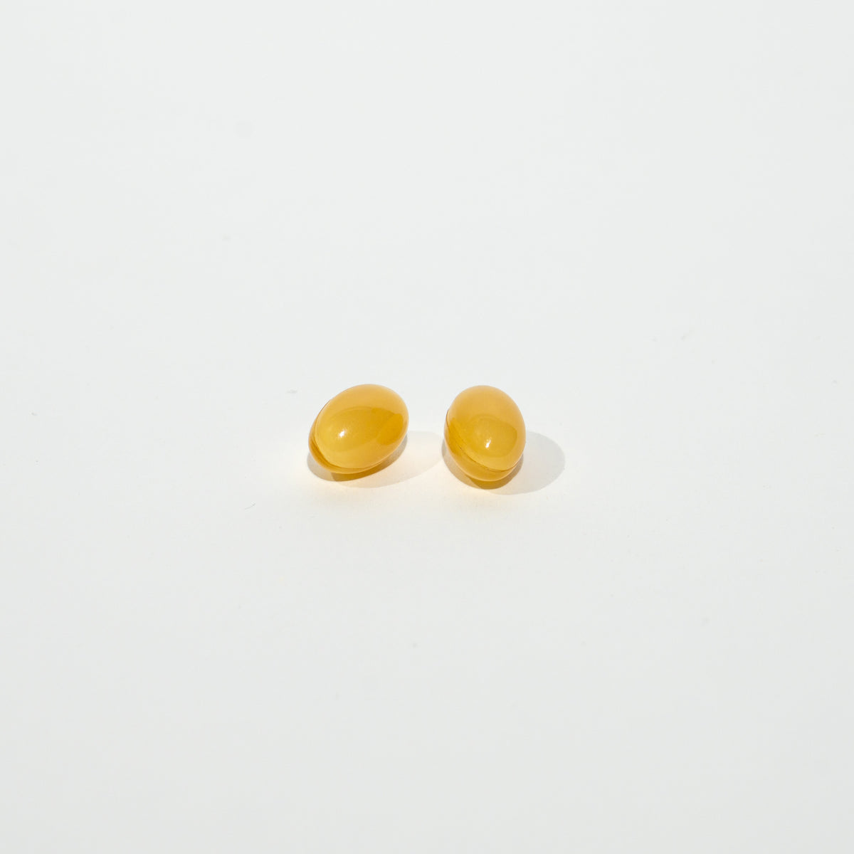 Pair of yellow softgels on a white background