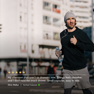 Man running outdoors with a water bottle, wearing a black jacket and gray beanie.