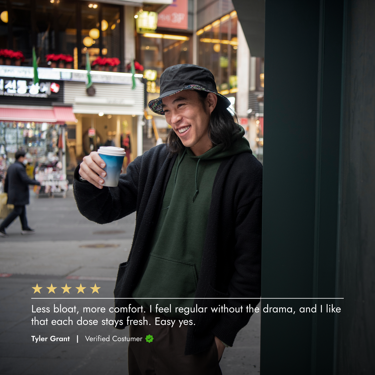 Person holding a coffee cup on a city street with a five-star rating and review text overlay.