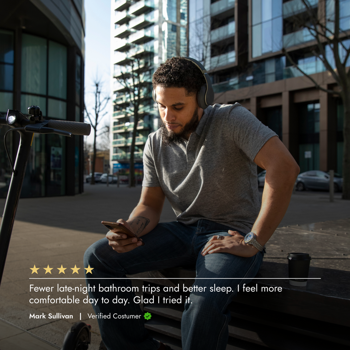 Man sitting on a bench with headphones, looking at his phone, in an urban setting.
Product review over the image