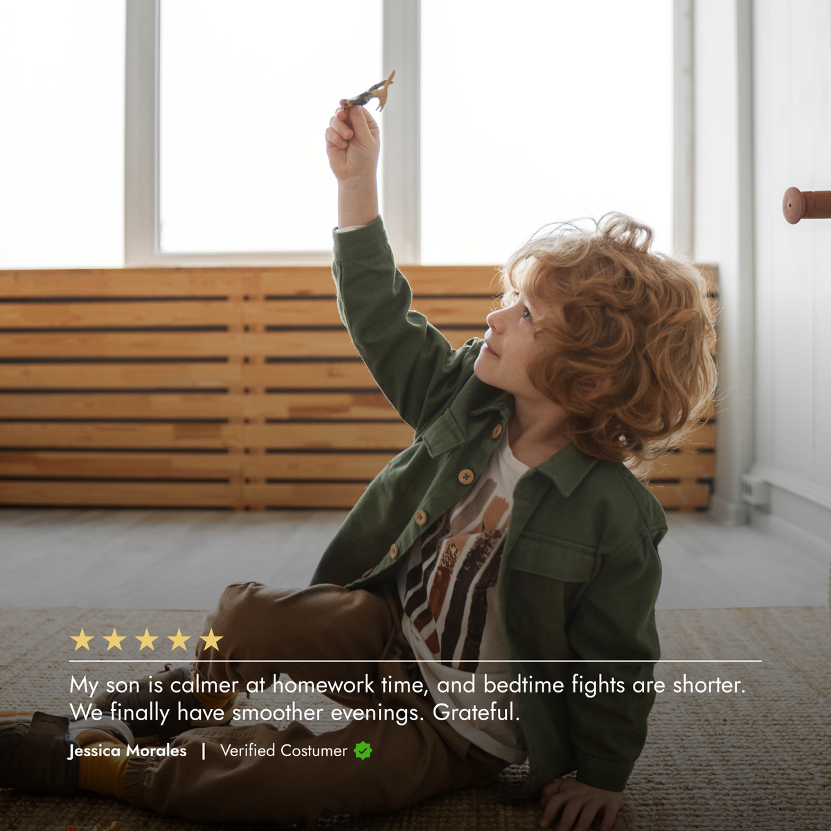 Child sitting on the floor with a toy airplane, looking out a window.