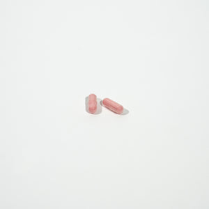 Two pink pills on a white background