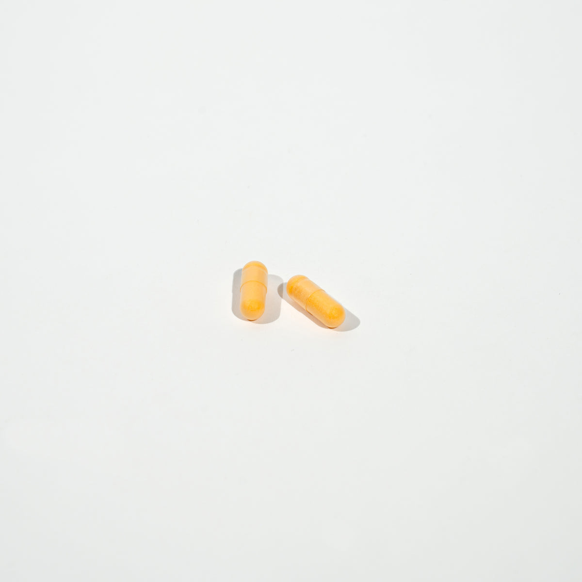 Two yellow pills on a white background