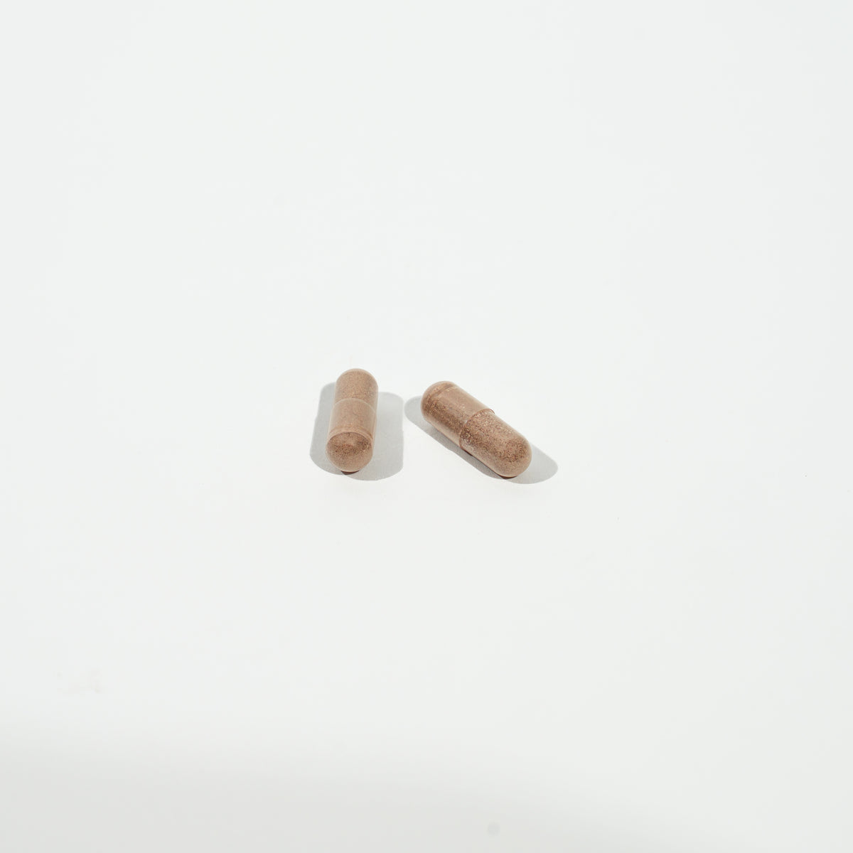 Two brown pills on a white background