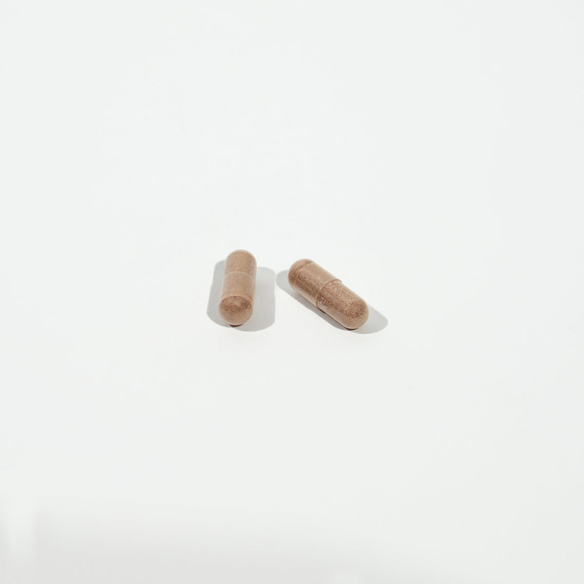 Two brown capsules on a white background