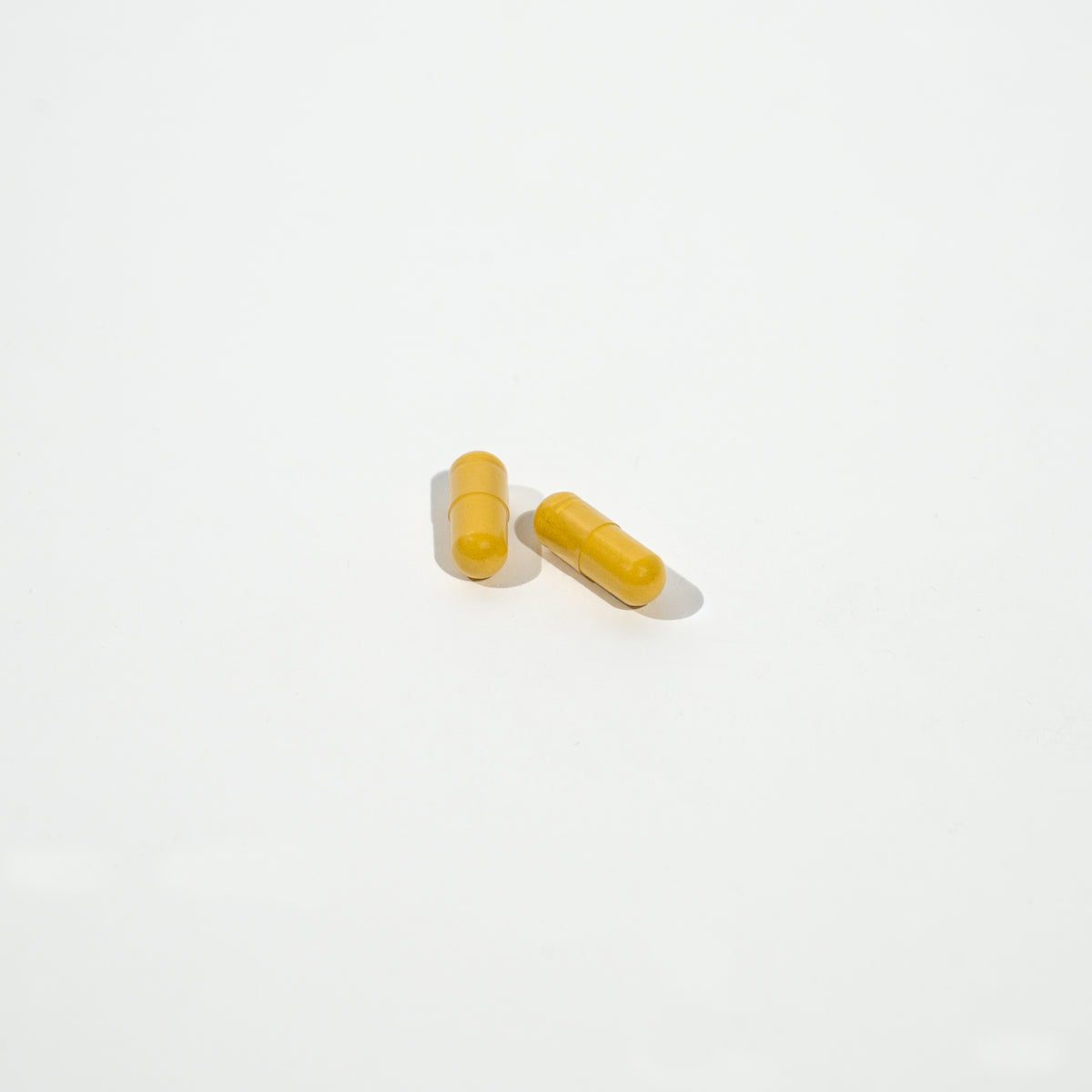 two yellow pills on a white background