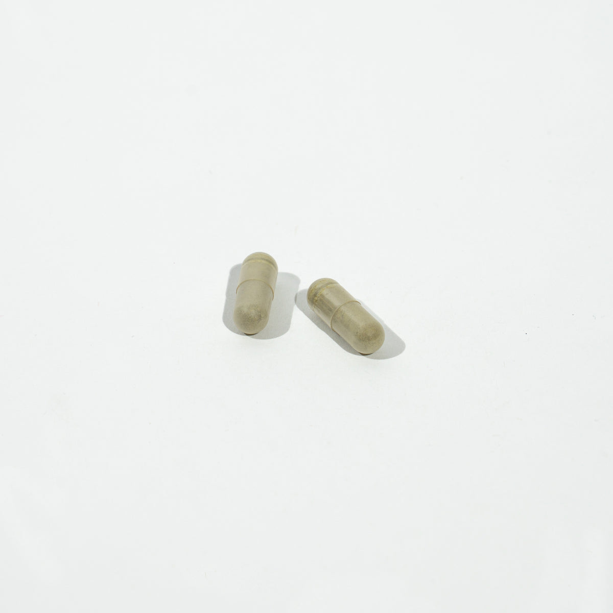 Two green capsules on a white background