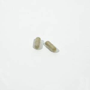 Two green capsules on a white background